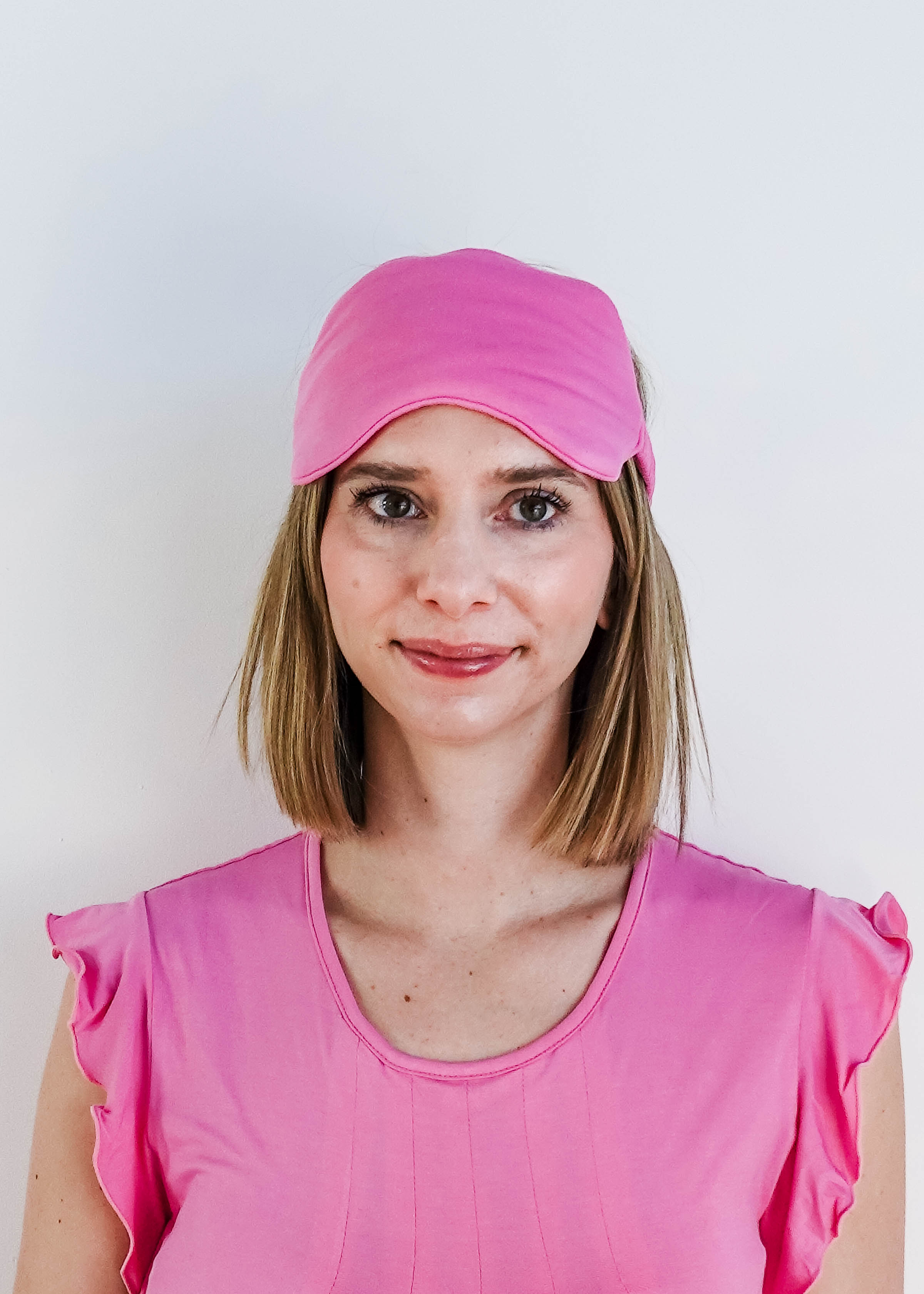 Bubblegum Pink Bamboo Sleep Eye Mask worn by a woman in pink top for comfortable sleep.