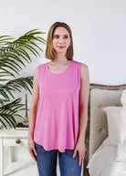 Woman wearing a Bubblegum Pink Essential Bamboo Tank Top in a stylish room setting with greenery.
