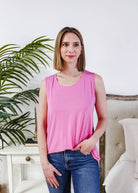Model wearing the Bubblegum Pink Essential Bamboo Tank Top with jeans and a plant in the background.