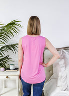 Woman wearing Bubblegum Pink Essential Bamboo Tank Top, showcasing the back view in a stylish bedroom setting.