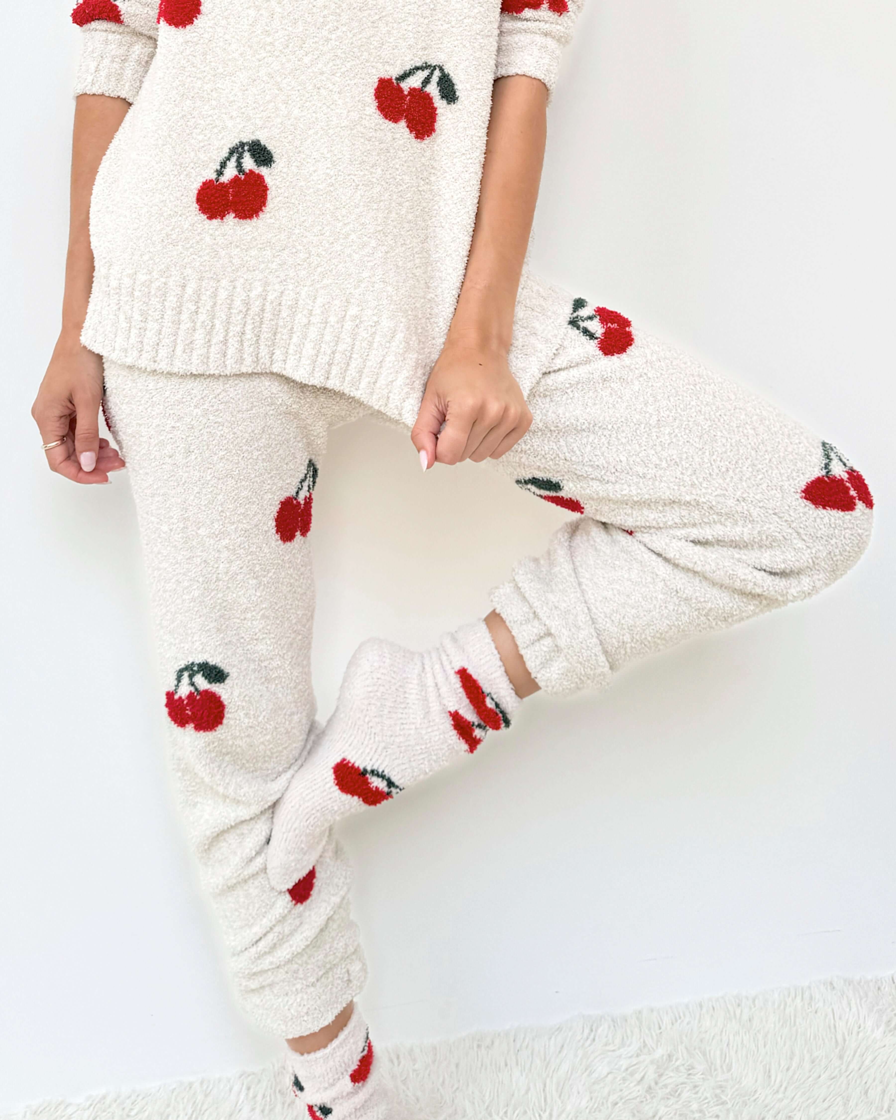 Woman wearing a Cloud-Soft Fuzzy Sweater Pajama Set Splendid with cherry patterns, showcasing cozy loungewear style. Showing leg fit and cuff