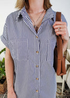 Person wearing a black and white striped dress holding a brown leather bag. Scarlett Ellie Collared Button-Up Short Sleeve Dress | Cloud Nine Pajamas