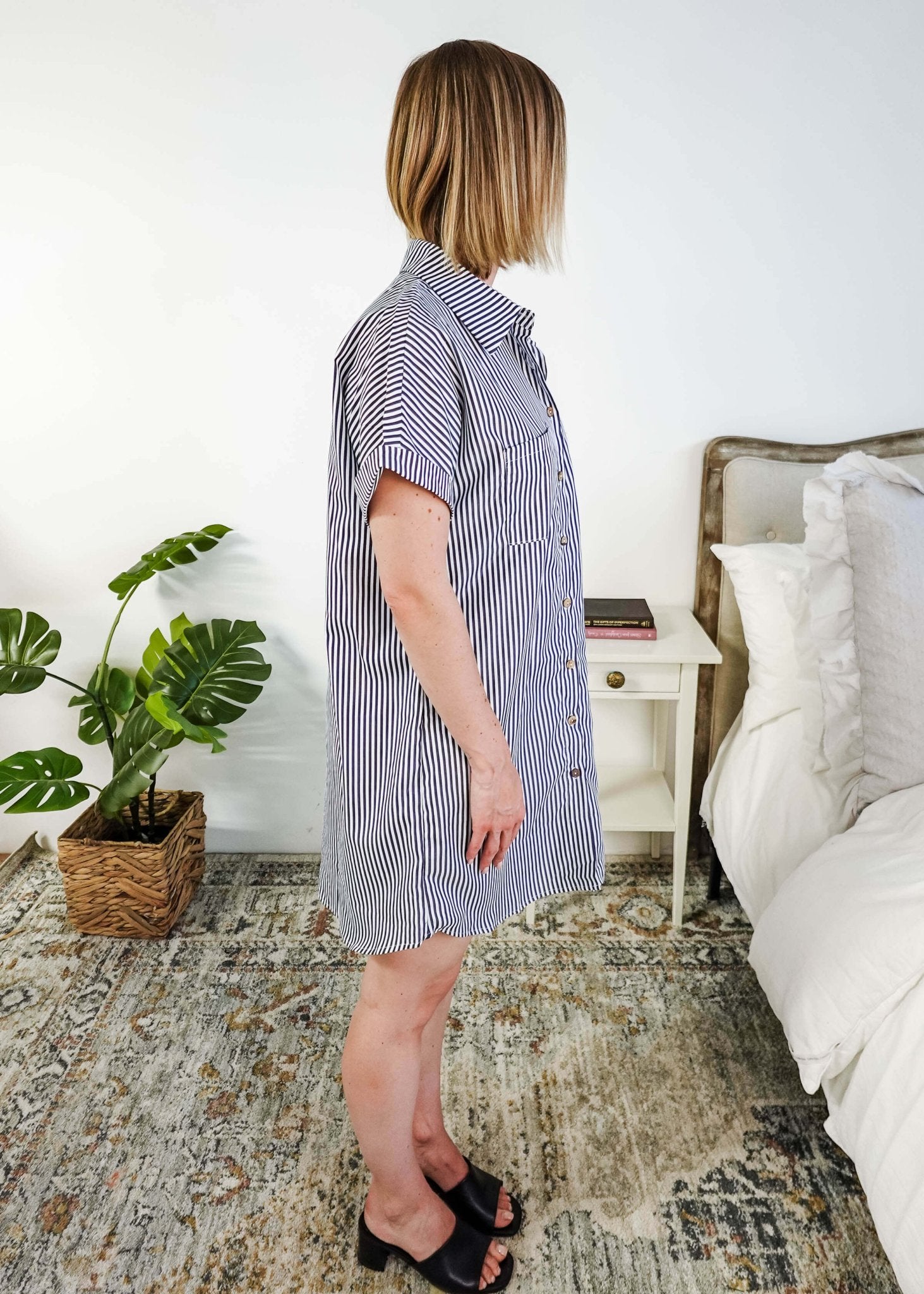 Woman wearing a blue and white striped dress in a bedroom setting. Scarlett Ellie Collared Button-Up Short Sleeve Dress | Cloud Nine Pajamas