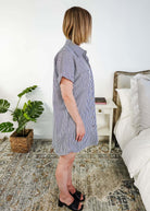 Woman wearing a blue and white striped dress in a bedroom setting. Scarlett Ellie Collared Button-Up Short Sleeve Dress | Cloud Nine Pajamas