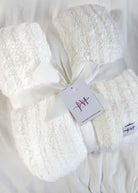 ivory white plush blanket on white background wrapped with a ribbon. Cozy Cabin Blanket – Oversized Ivory Plush Throw (75″ × 52″)