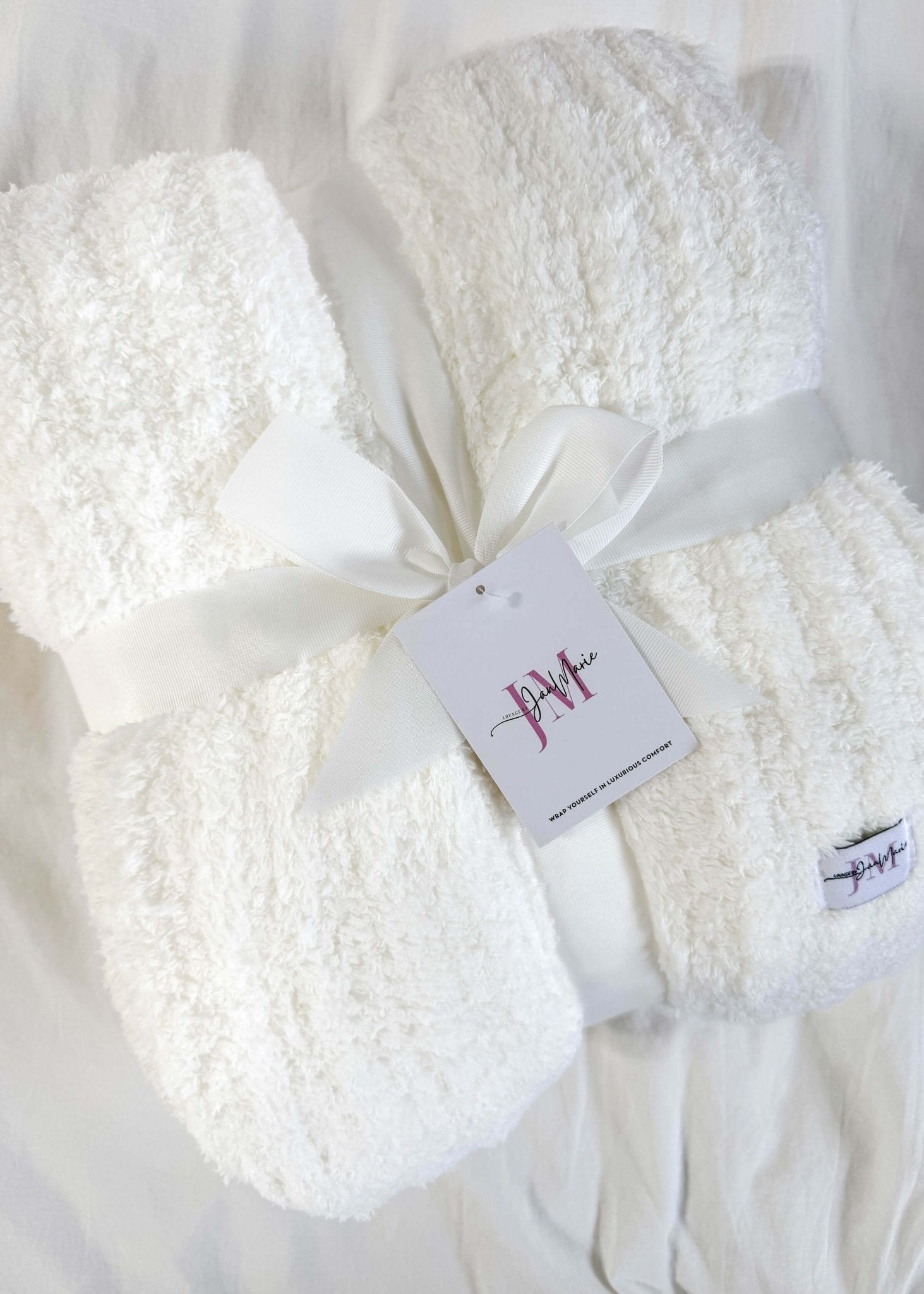 ivory white plush blanket on white background wrapped with a ribbon. Cozy Cabin Blanket – Oversized Ivory Plush Throw (75″ × 52″)