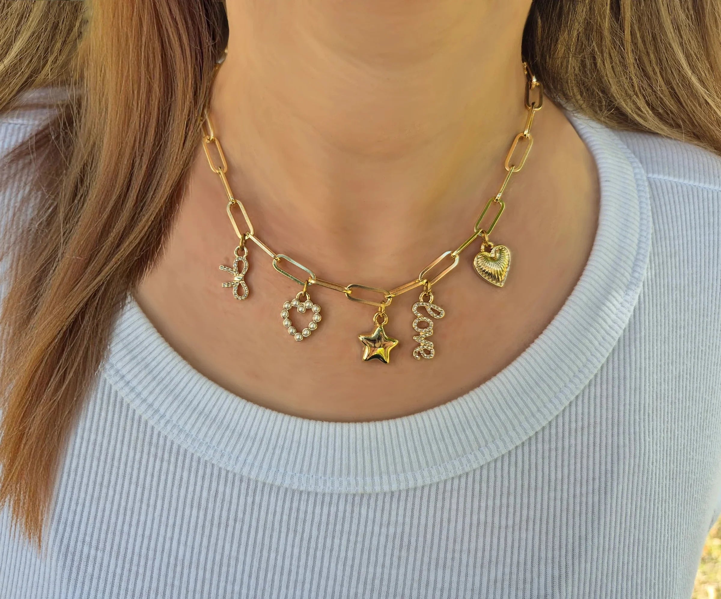 Bella Charm Necklace in 14K Gold featuring five charms: heart, star, bow, love script, and pearl heart.