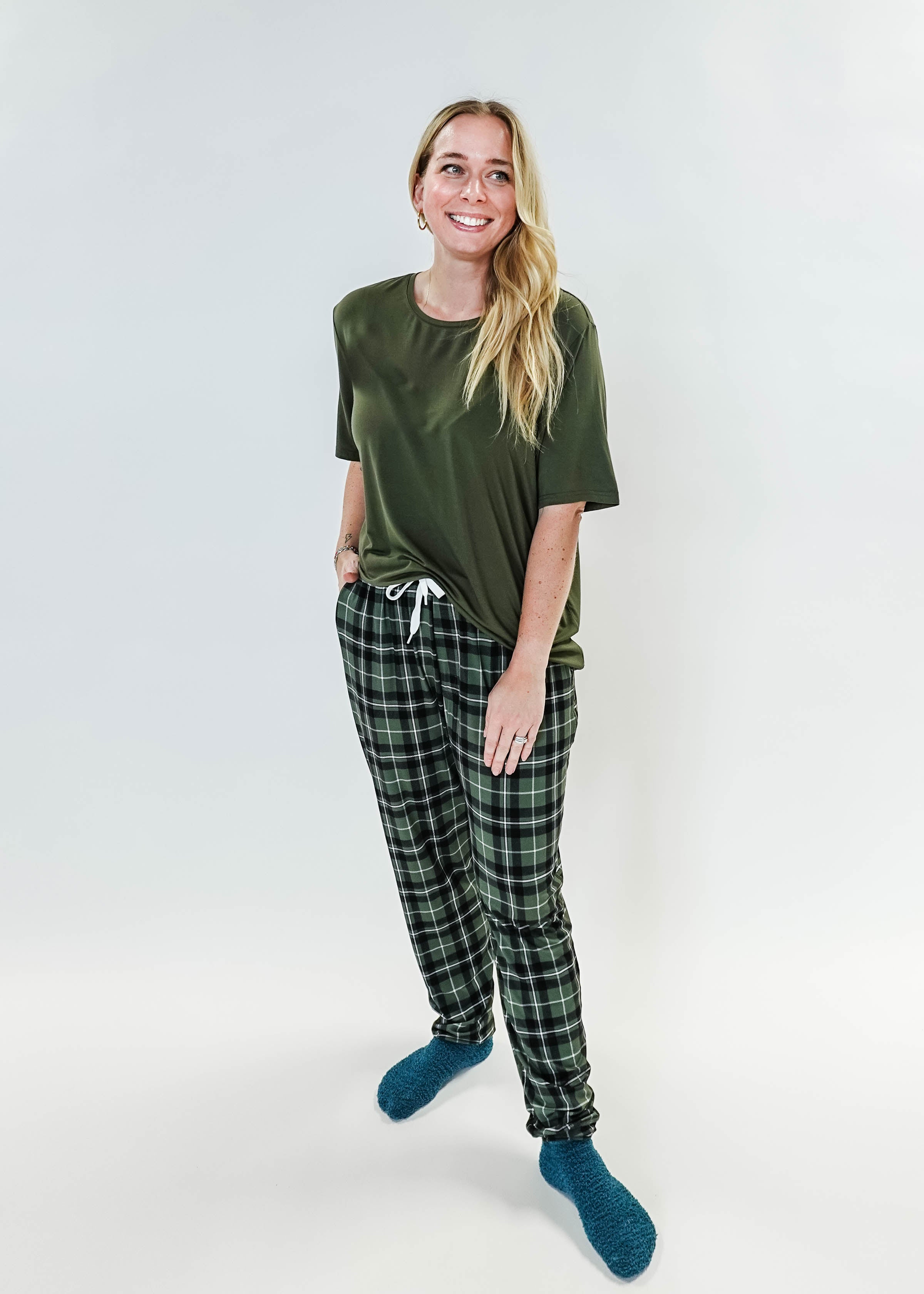 Model wearing Green Plaid Unisex Bamboo Jogger from Bob's Sleepwear Co. with a casual top and cozy socks.