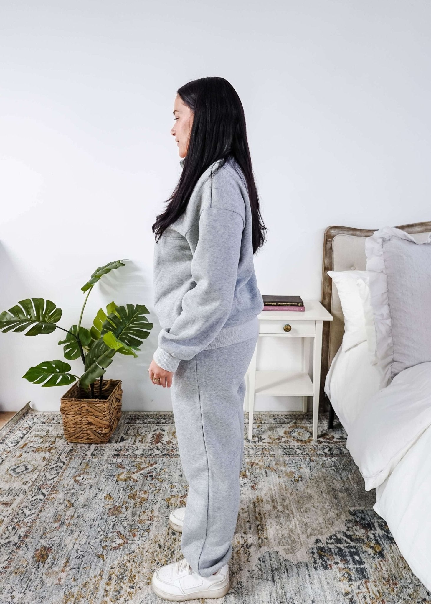 Woman wearing a grey sweatsuit standing in a bedroom with a plant and bed in the background, Scarlett Ellie Half-Zip Sweatsuit Set | Cloud Nine Pajamas