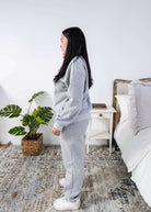 Woman wearing a grey sweatsuit standing in a bedroom with a plant and bed in the background, Scarlett Ellie Half-Zip Sweatsuit Set | Cloud Nine Pajamas