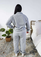 The back of a woman wearing a grey sweatsuit standing in a bedroom with a plant and bed in the background Scarlett Ellie Half-Zip Sweatsuit Set | Cloud Nine Pajamas