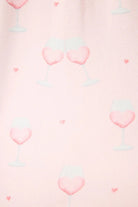 Happy Hour Wine Glass Print 3-Piece PJ Set | PJ Salvage women's wine glass print pj set in pink - button up long sleeve top, straight leg pants, and matching eye mask close up of the pink wine print, the "wine" looks like a heart and there are small hearts around the glass. 