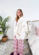 Essential Hooded Fluffy Cozy Cardigan with Pockets worn by a woman with floral pajamas in a cozy bedroom setting.