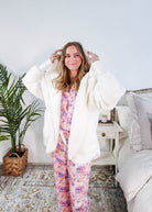 Essential Hooded Fluffy Cozy Cardigan with Pockets worn by a woman with floral pajamas in a cozy bedroom setting.