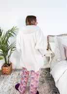 Essential Hooded Fluffy Cozy Cardigan with Pockets worn by a woman with floral pajamas in a cozy bedroom setting showing back of cardigan