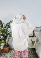 Essential Hooded Fluffy Cozy Cardigan with Pockets worn by a woman with floral pajamas in a cozy bedroom setting.