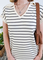 Person wearing a black and white striped dress with a brown bag.