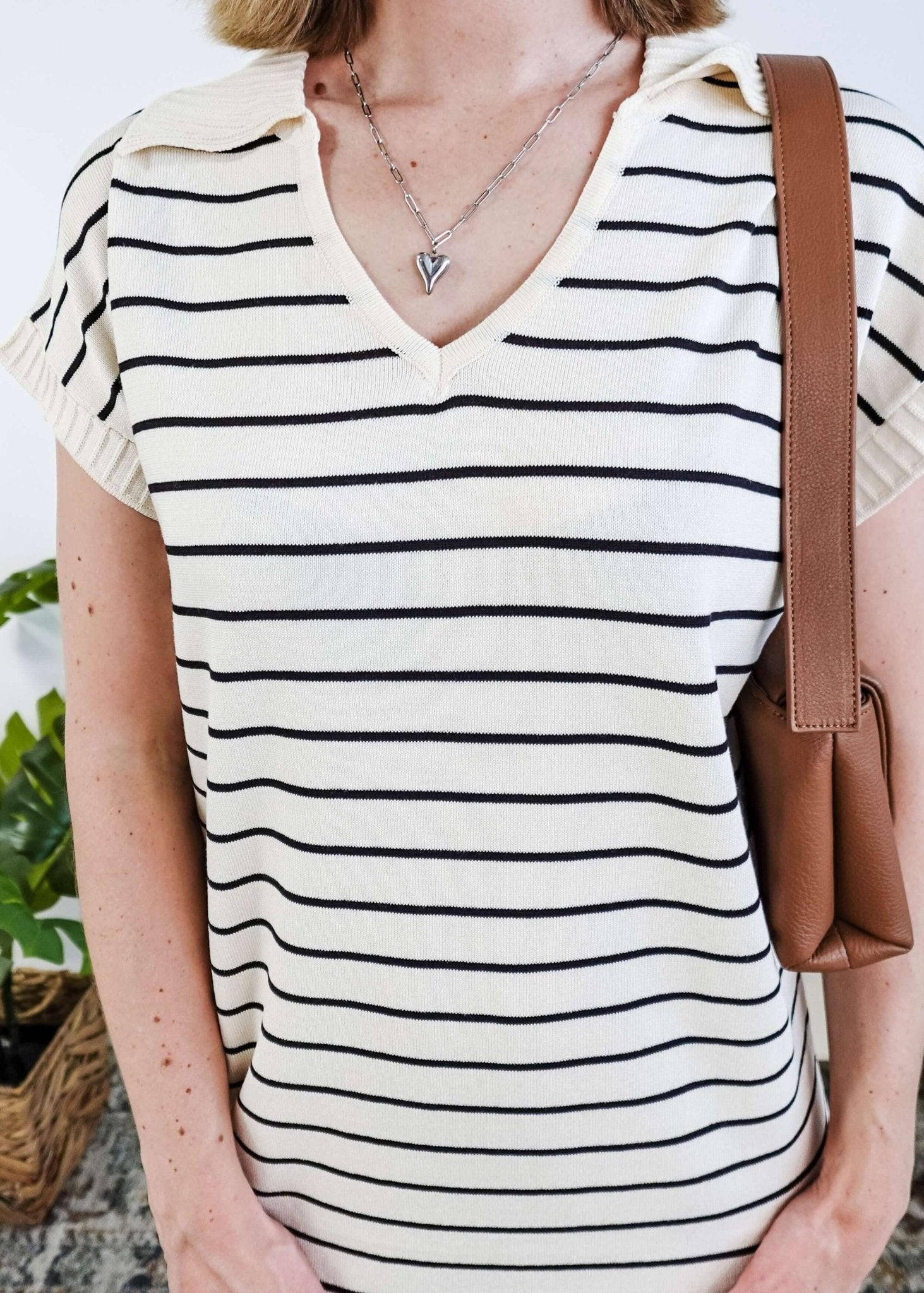 Person wearing a black and white striped dress with a brown bag.