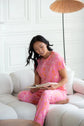 Model wearing Latte Love Floral Print Cotton-Modal Relaxed Set Drop Shoulder Tee & Jogger Set while reading on a couch.