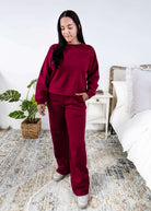 Woman wearing a red lounge outfit standing in a bedroom.
