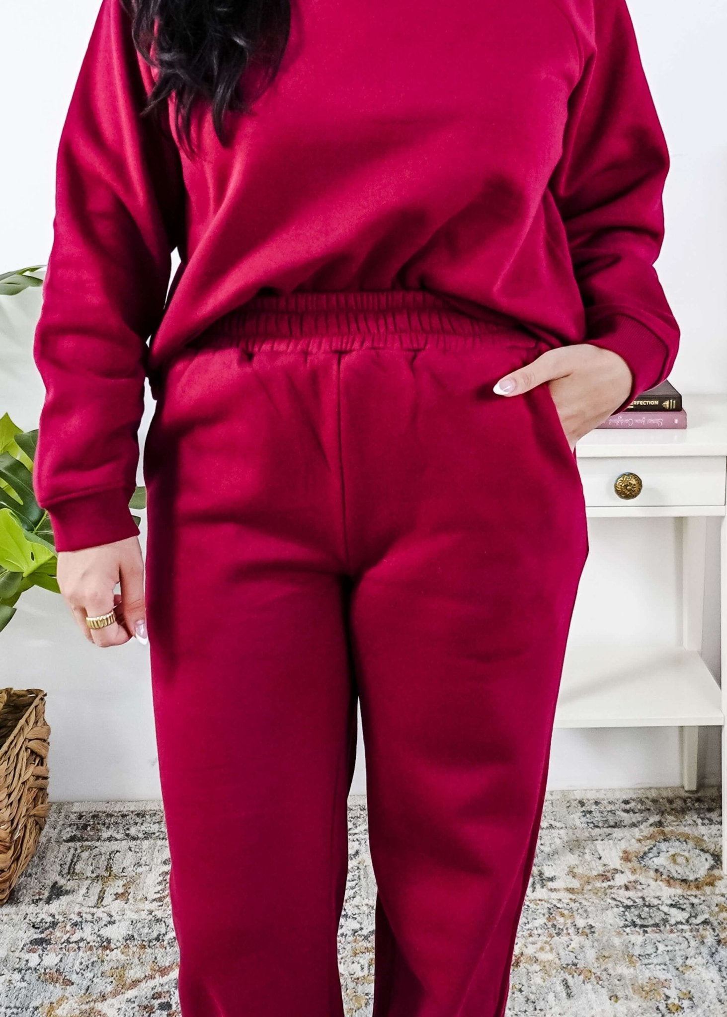 Woman wearing a red lounge outfit standing in a bedroom.