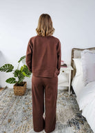 Person wearing a brown sweatsuit in a bedroom setting