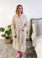 Sand Beige Chenille Cloud Spa Robe – Plush Stretch Robe with Pockets model wearing the robe standing next to a bed showing length