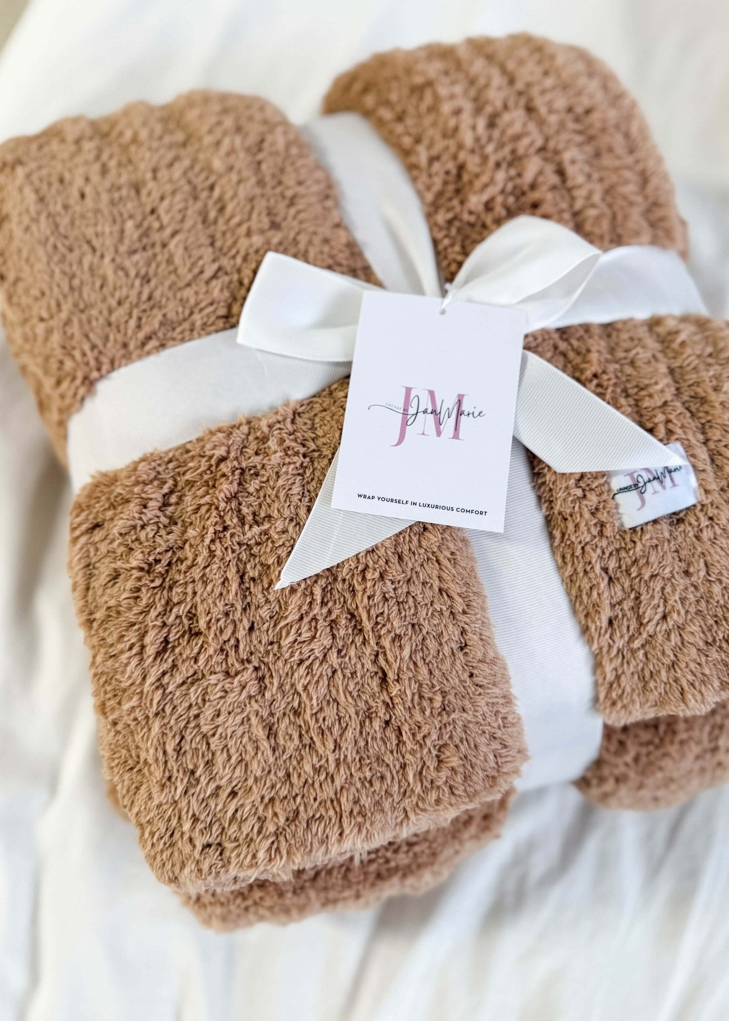 Mocha Brown Cozy Cabin Blanket with a white ribbon and tag on a light background