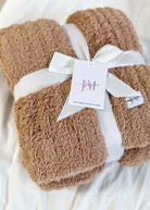 Mocha Brown Cozy Cabin Blanket with a white ribbon and tag on a light background