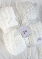 ivory white plush blanket on white background wrapped with a ribbon