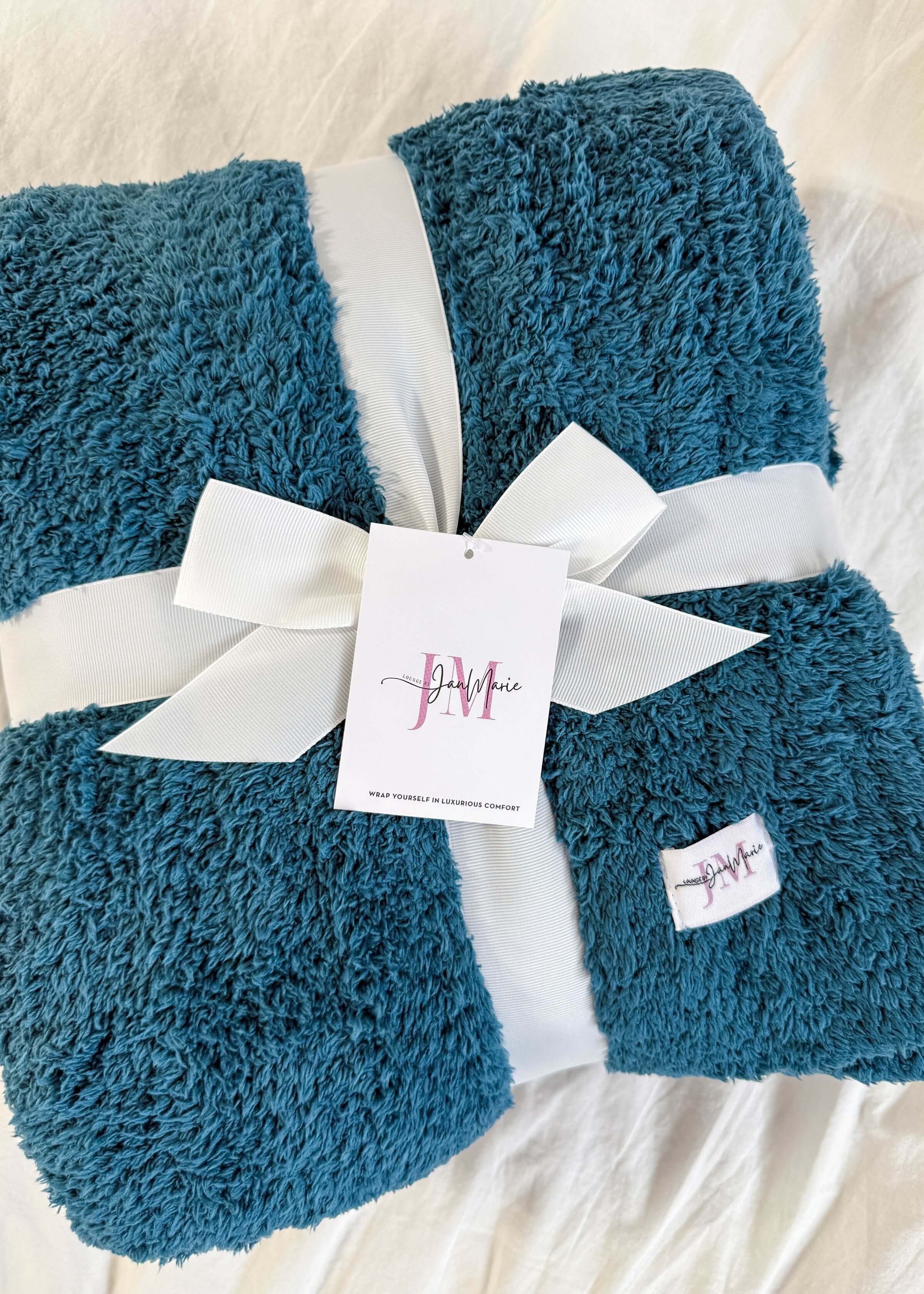 teal blue plush blanket rapped in ribbon on white background