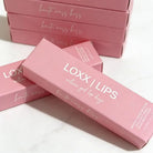 LOXX LIPS Peptide Lip Gloss Haute Mess Kiss Pink Tint packaging displayed on a marble surface.