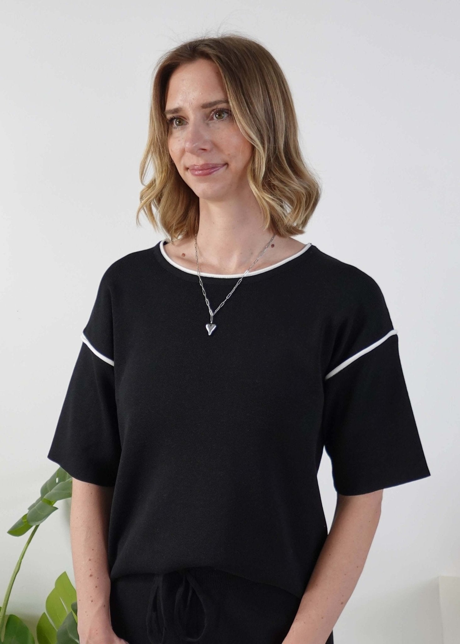 Woman wearing a black top with white trim against a white background