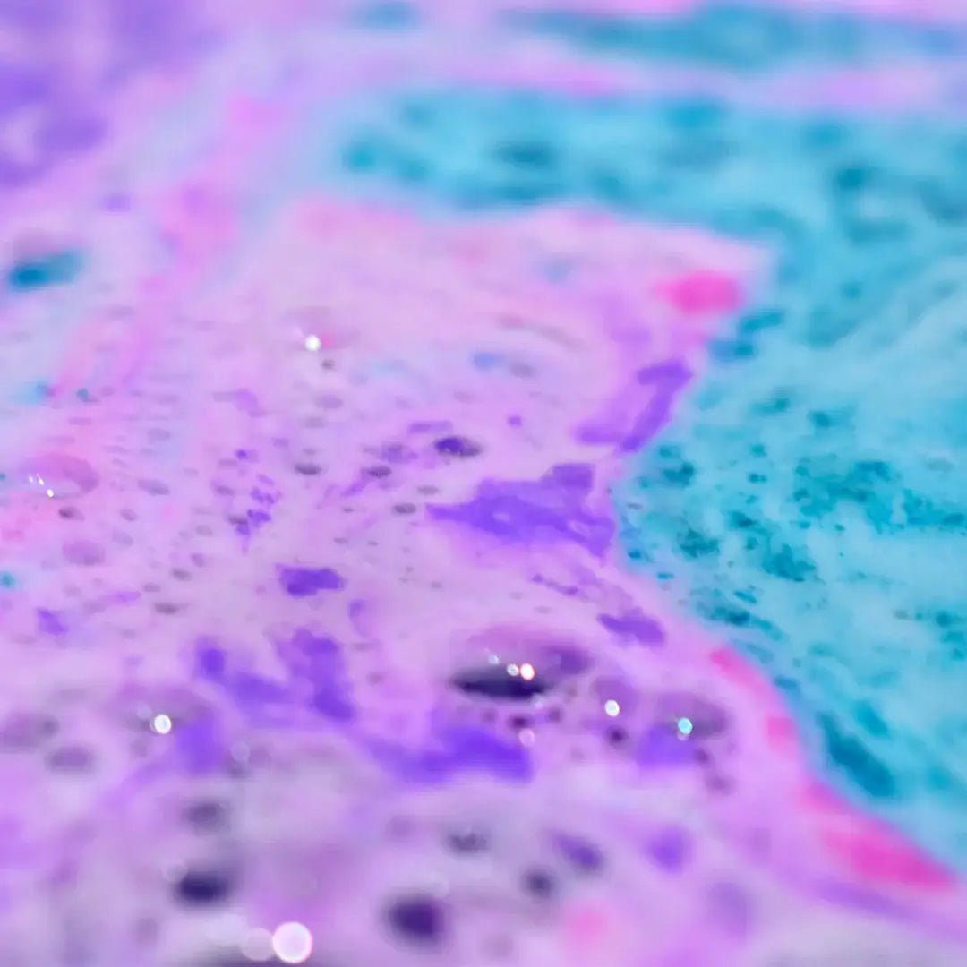 Colorful bath water showcasing the fizz and foam of Mermaid Bath Bomb Crumble in hues of purple and blue.