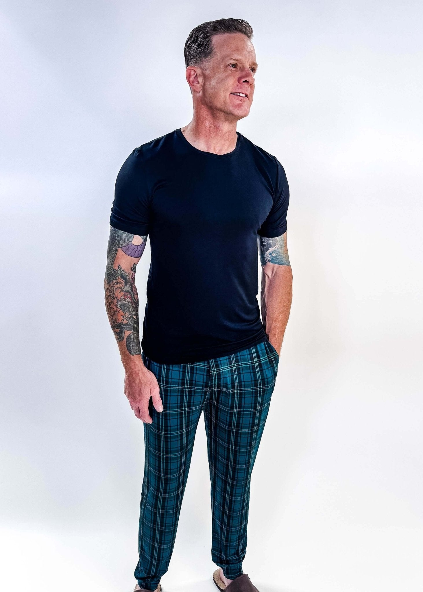 Man wearing Midnight Plaid Unisex Bamboo Joggers and a black shirt, showcasing comfort and style.