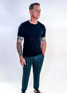 Man wearing Midnight Plaid Unisex Bamboo Joggers and a black shirt, showcasing comfort and style.