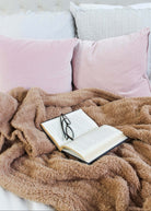 Mocha Brown Cozy Cabin Blanket Open book with glasses on a fluffy brown blanket on a bed with pink pillows.
