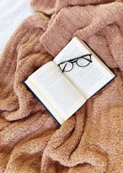 Mocha Brown Cozy Cabin Blanket laid across a bed with a book