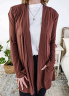 Person wearing a brown cardigan over a white shirt in a casual setting. Scarlett Ellie Summer Open Lightweight Cardigan | Cloud Nine Pajamas