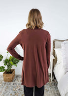 Person wearing a brown long-sleeve cardigan in a bedroom setting Scarlett Ellie Summer Open Lightweight Cardigan | Cloud Nine Pajamas