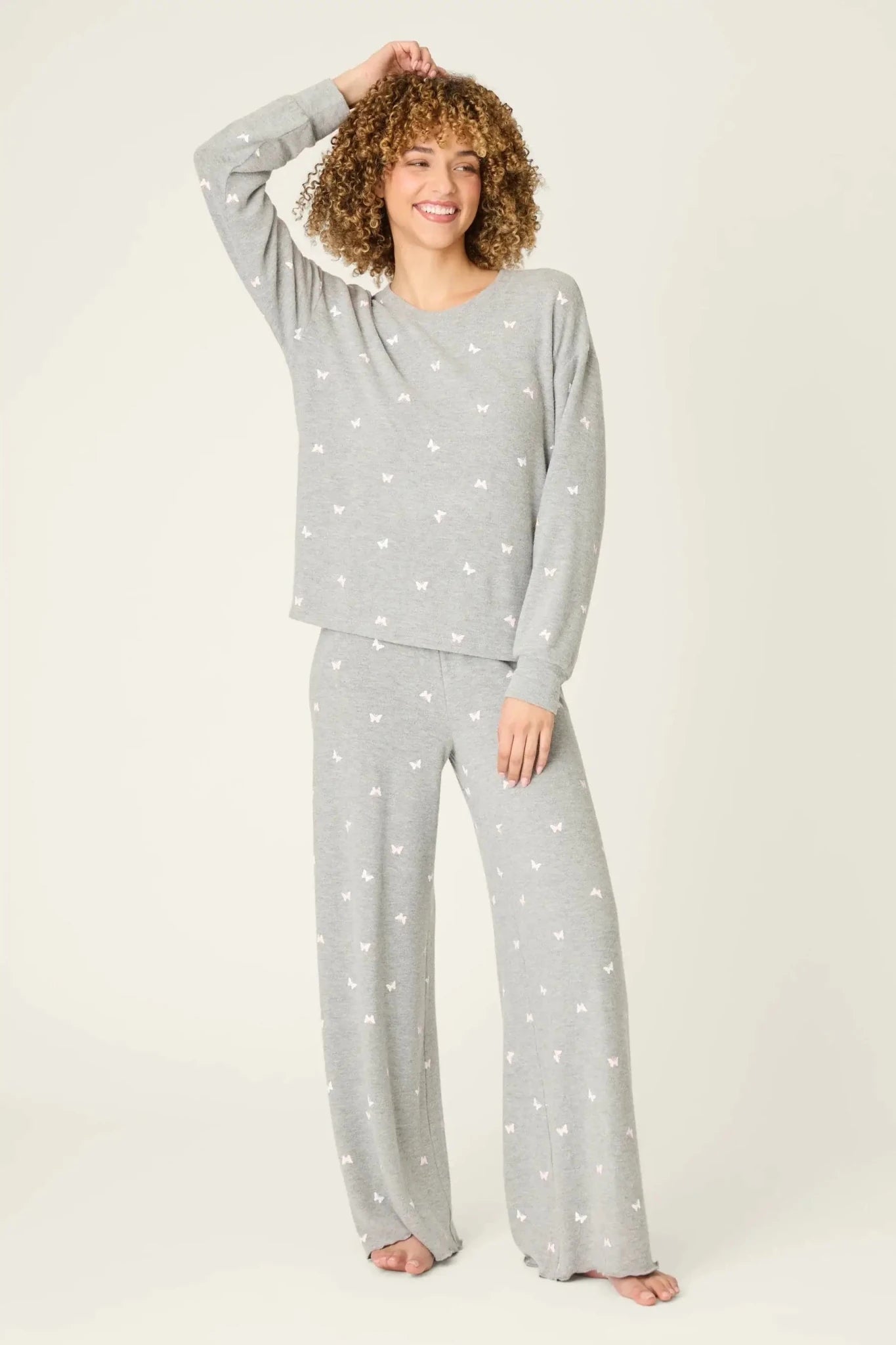 Woman wearing the PJ Salvage Peachy Butterfly Kisses Lounge Set featuring a cozy top and wide-leg pants in heathered grey.