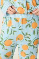 Model wearing PJ Salvage Citrus Dreams 3-Piece PJ Set featuring orange design with matching eye mask. close up of pant waist