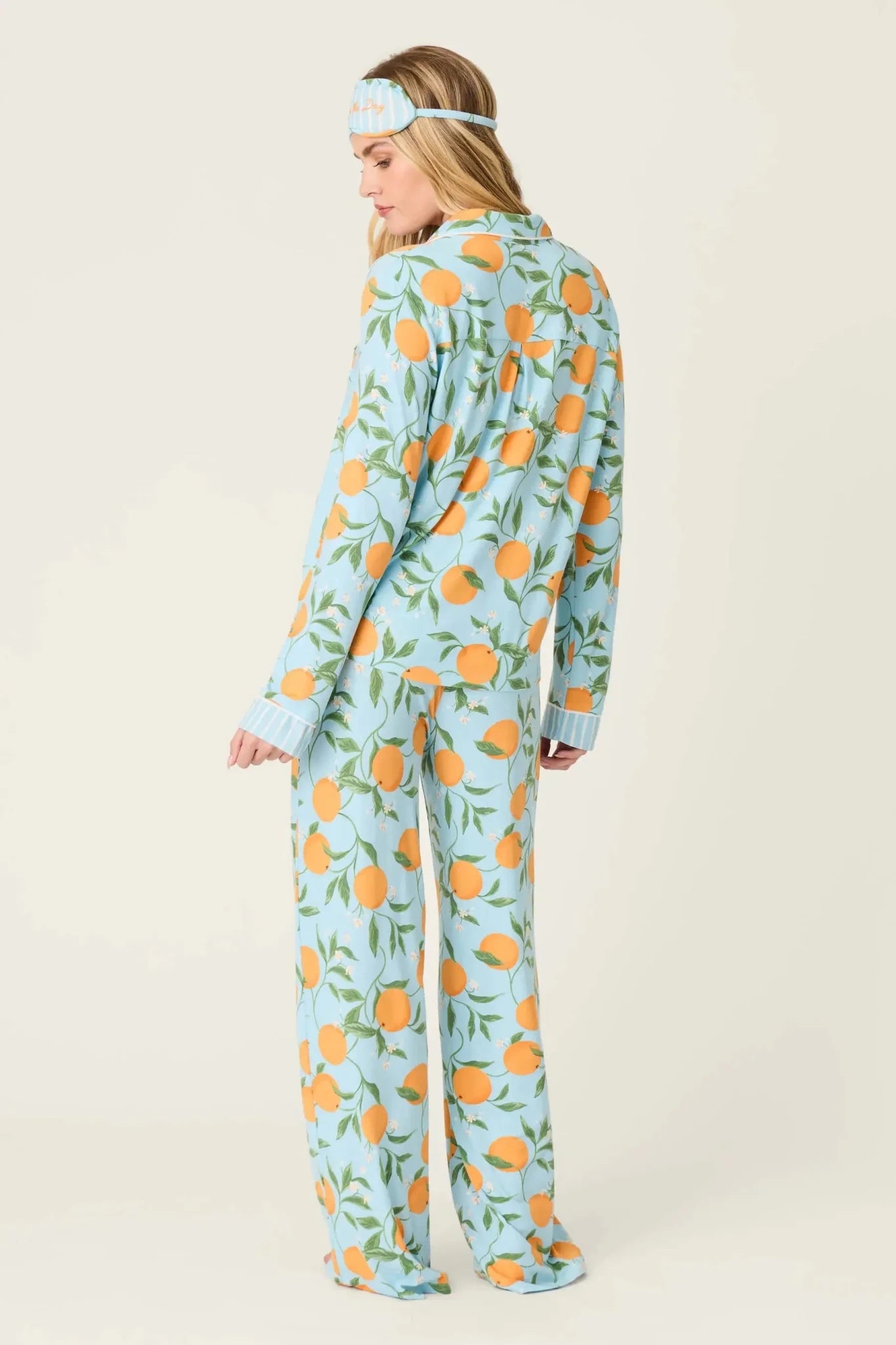 Model wearing PJ Salvage Citrus Dreams 3-Piece PJ Set featuring orange design with matching eye mask. Back View