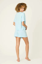 PJ SALVAGE Graphic Print Softee Tee & Short Lounge Set in "Breakfast Club" graphic tee shirt in light blue. Model stands against a light background in a back view profile shot