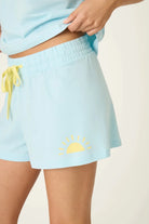 PJ SALVAGE Graphic Print Softee Tee & Short Lounge Set in "Breakfast Club" graphic tee shirt in light blue. Model stands against a light background in a close up of short profile shot