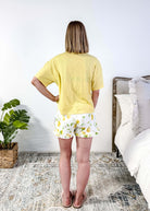 PJ SALVAGE — La Dolce Spritz Limoncello Graphic Tee & Lemon Zest Short Set shown on model in bedroom setting, full length shot of back