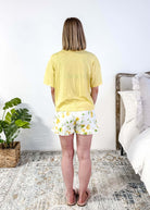 PJ SALVAGE — La Dolce Spritz Limoncello Graphic Tee & Lemon Zest Short Set shown on model in bedroom setting, full length shot of the back profile