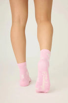 Pair of PJ Salvage Bright Pink Fuzzy Crew Socks with a whimsical all-over white bow print. Showing the plush texture and grip soles.