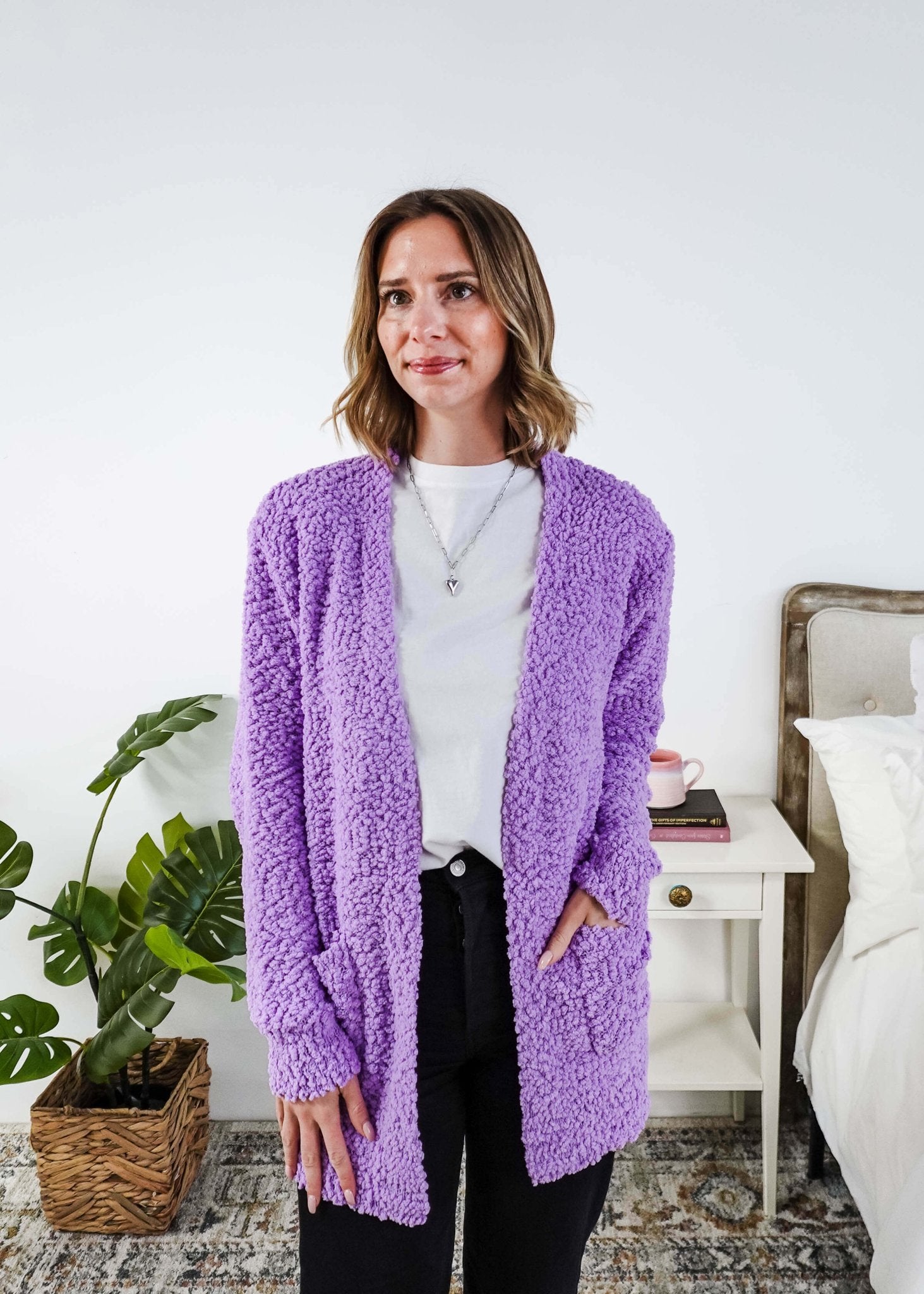 Popcorn Texture Open Summer Cardigan in lilac purple colour shown on model  with jeans and white tee shirt, in a bedroom setting. 