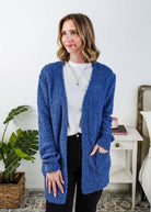 Popcorn Texture Open Summer Cardigan in blue, shown on model in a bedroom setting with hand in pocket